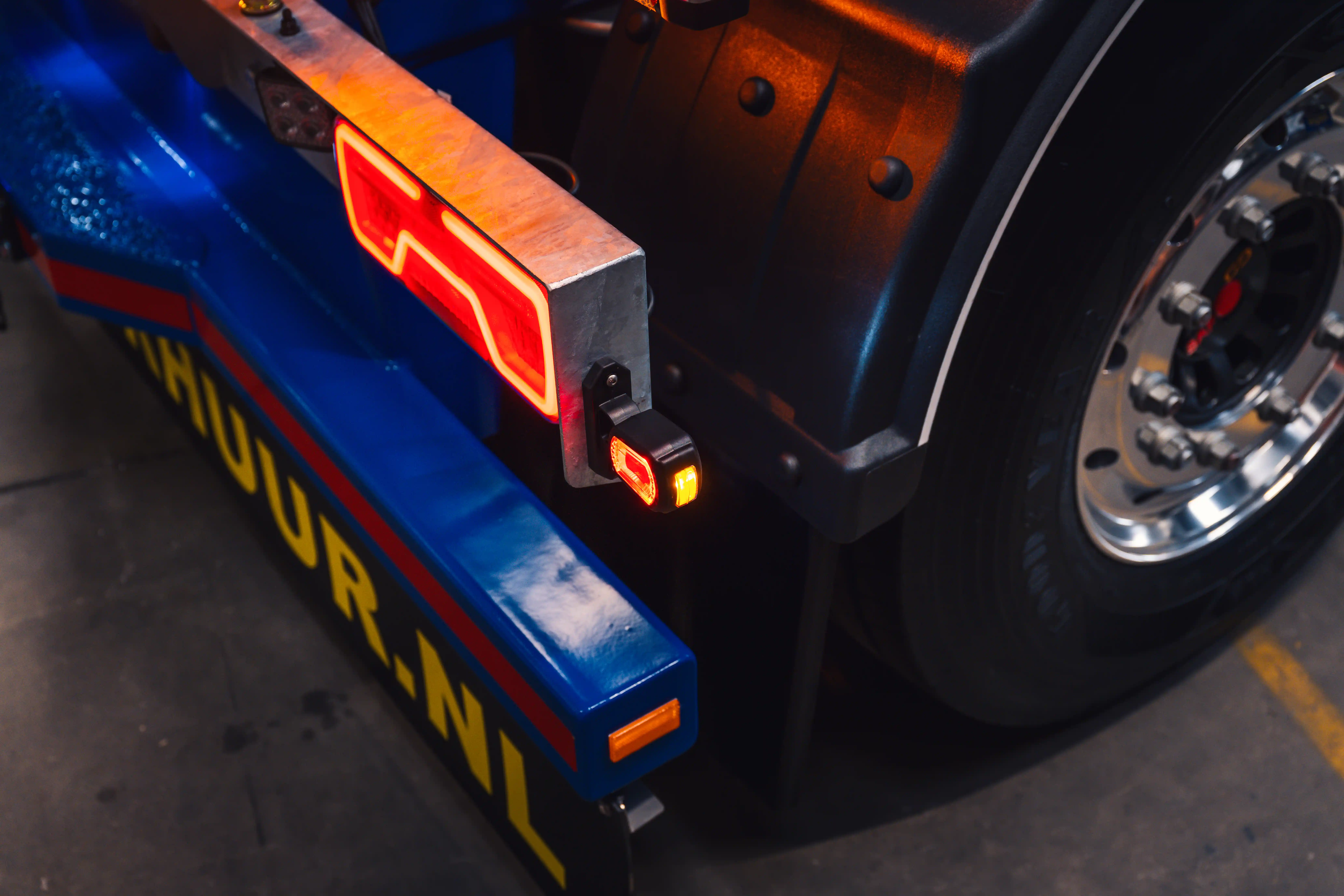 Side view of a custom-lit show trailer at an indoor truck festival