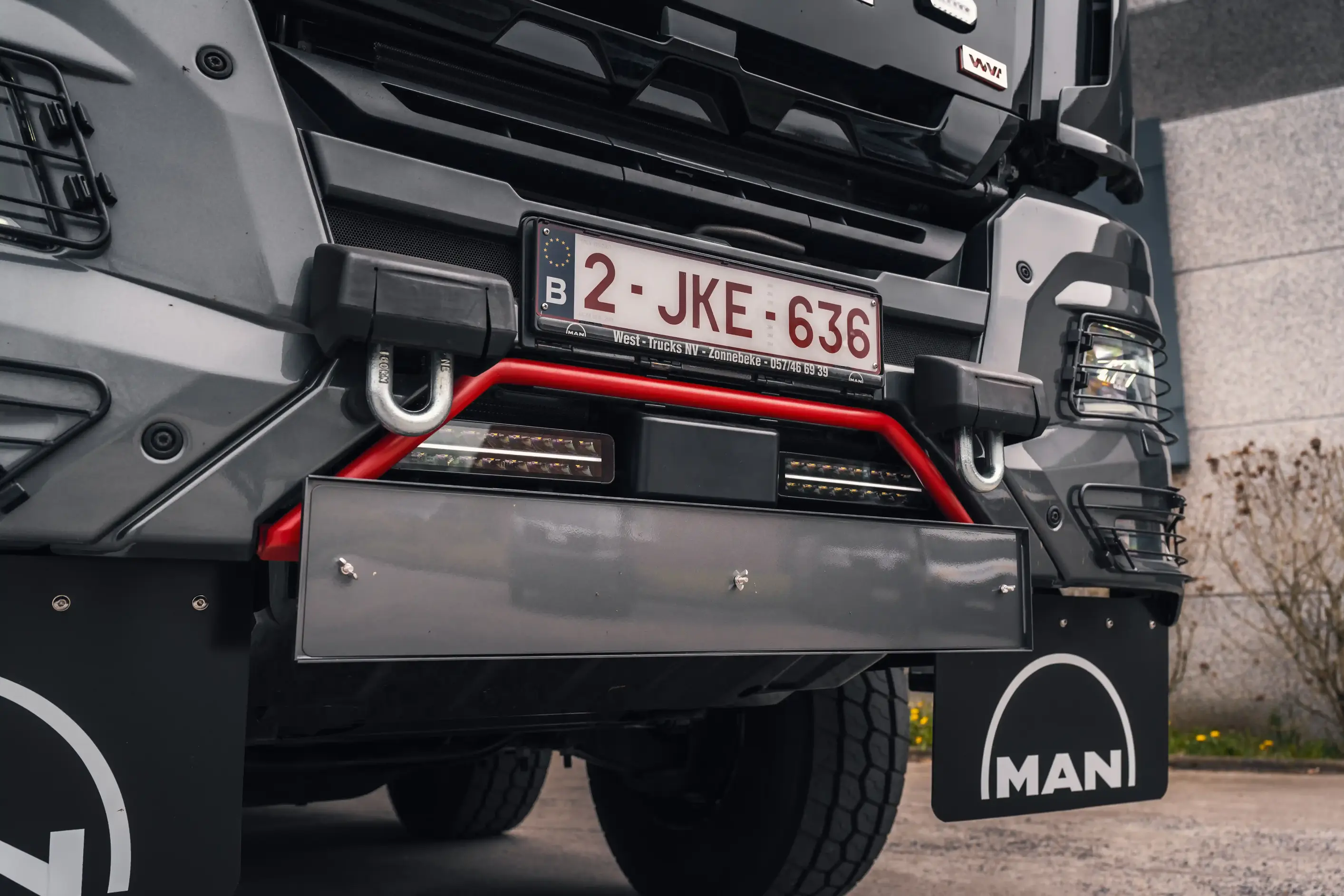 Heavy 8x8 MAN truck cab photographed at dusk, with auxiliary LED lighting lit along the roof bar