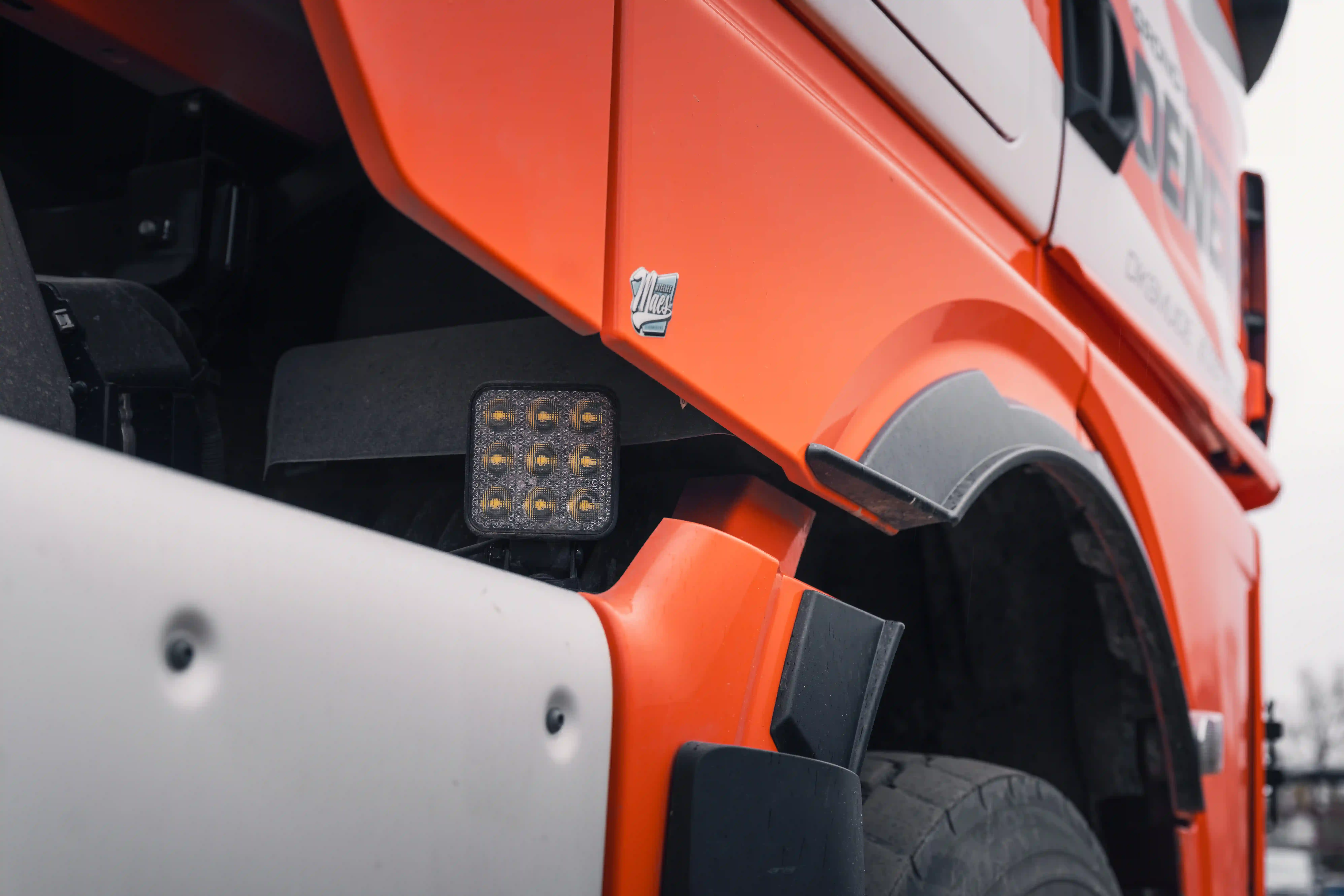 Tipper truck parked on a construction site at dusk with auxiliary lighting illuminated